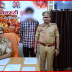 एक पुलिस अधिकारी गिरफ्तार आरोपी के साथ, हाथ में मोबाइल फोन।