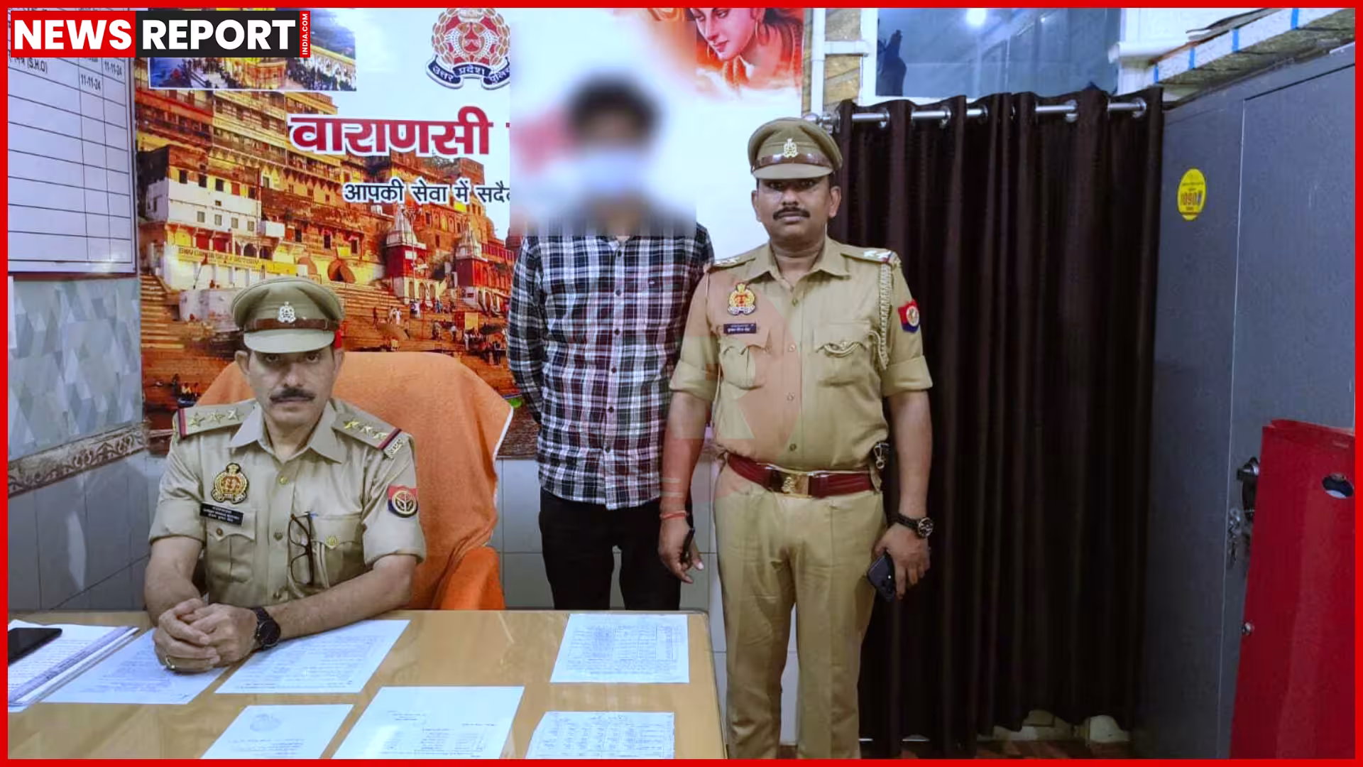 एक पुलिस अधिकारी गिरफ्तार आरोपी के साथ, हाथ में मोबाइल फोन।