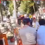 शहीद स्मारक में फूल अर्पित करते हुए गणमान्य व्यक्ति और पास में बहस करते विधायक