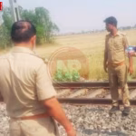 चंदौली में रेलवे ट्रैक पर पड़ा युवक का शव, पास में पुलिसकर्मी जांच करते हुए