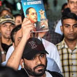 अभिजीत दीपके जंतर मंतर पर प्रदर्शन में समर्थकों के साथ, हाथ में पुस्तक लिए हुए