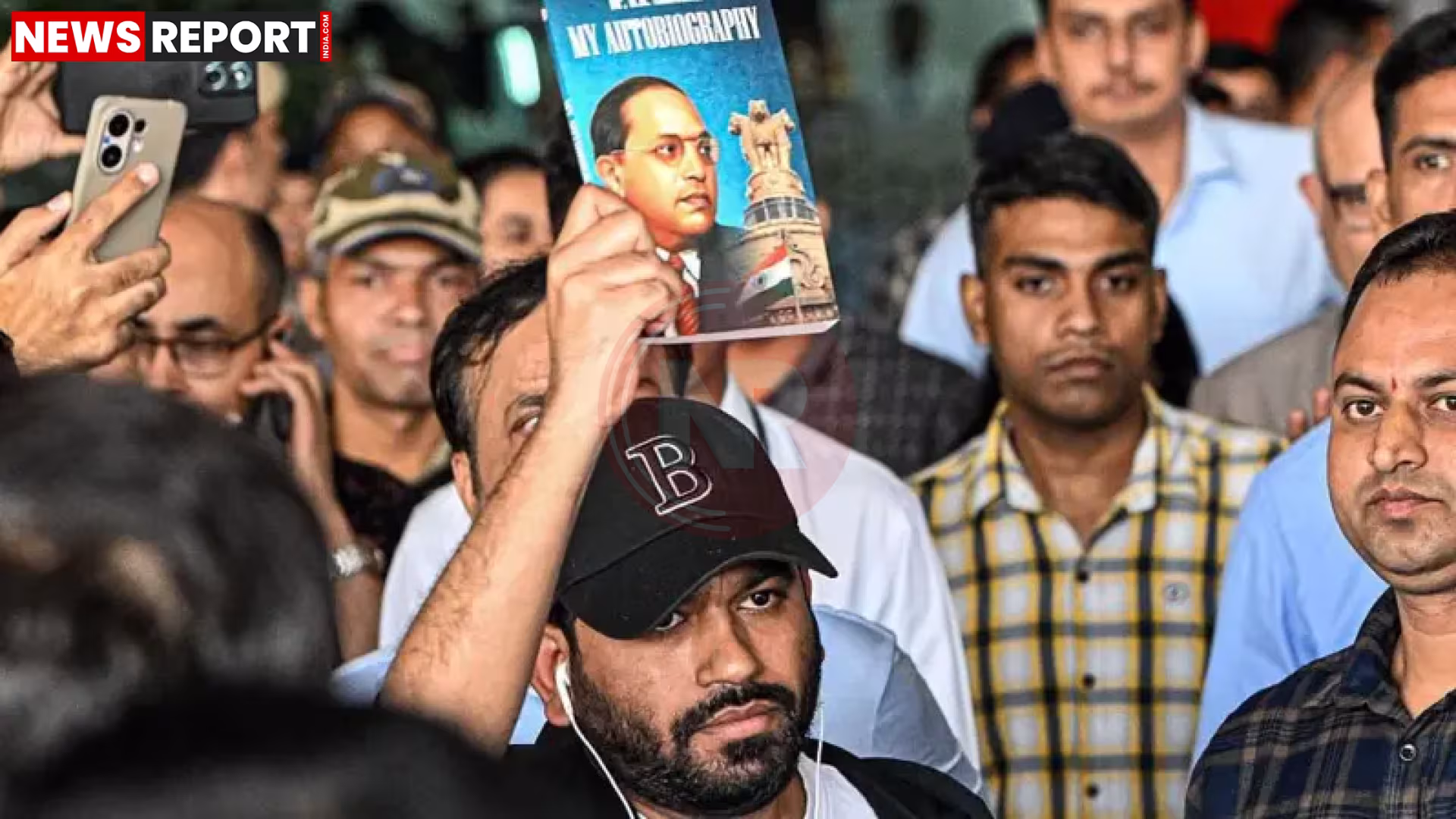 अभिजीत दीपके जंतर मंतर पर प्रदर्शन में समर्थकों के साथ, हाथ में पुस्तक लिए हुए