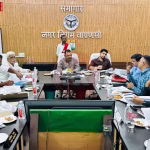 वाराणसी नगर निगम की डिजिटल सेवाओं को दर्शाते हुए एक हेल्पलाइन नंबर और शहर का दृश्य