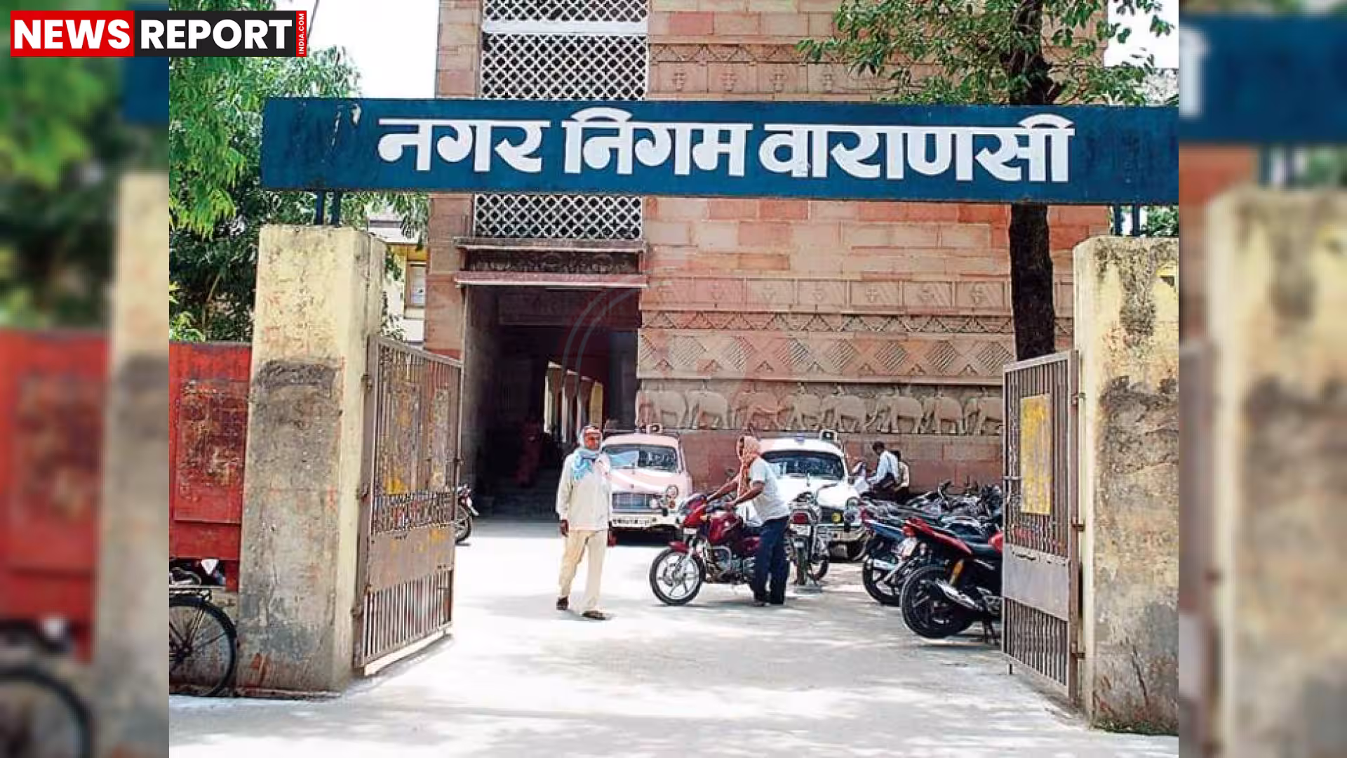 बारिश में जलभराव के दौरान एक खुले मैनहोल के पास चेतावनी बोर्ड और आसपास लोग।