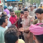 एक व्यस्त हाईवे पर क्षतिग्रस्त ट्रक और पुलिसकर्मियों के साथ आक्रोशित ग्रामीणों की भीड़