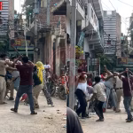 पुलिसकर्मियों पर हमला करते हुए लोगों का समूह, जिसमें मिर्च पाउडर और लाठी-डंडों का इस्तेमाल हो रहा है।
