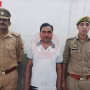 कानपुर में बच्चा चोरी के आरोप में गिरफ्तार बिजली विभाग के एसडीओ आर के वर्मा को पुलिस ले जाते हुए।