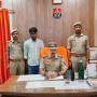 पुलिस अधिकारी नाबालिग अपहरण के आरोपी को गिरफ्तार कर ले जाते हुए, पास में पुलिस वाहन।