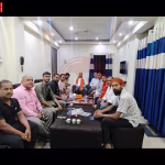 रामनगर में मां अंबे पूजा समिति की बैठक की तस्वीर, जिसमें सदस्य चर्चा करते दिख रहे हैं।